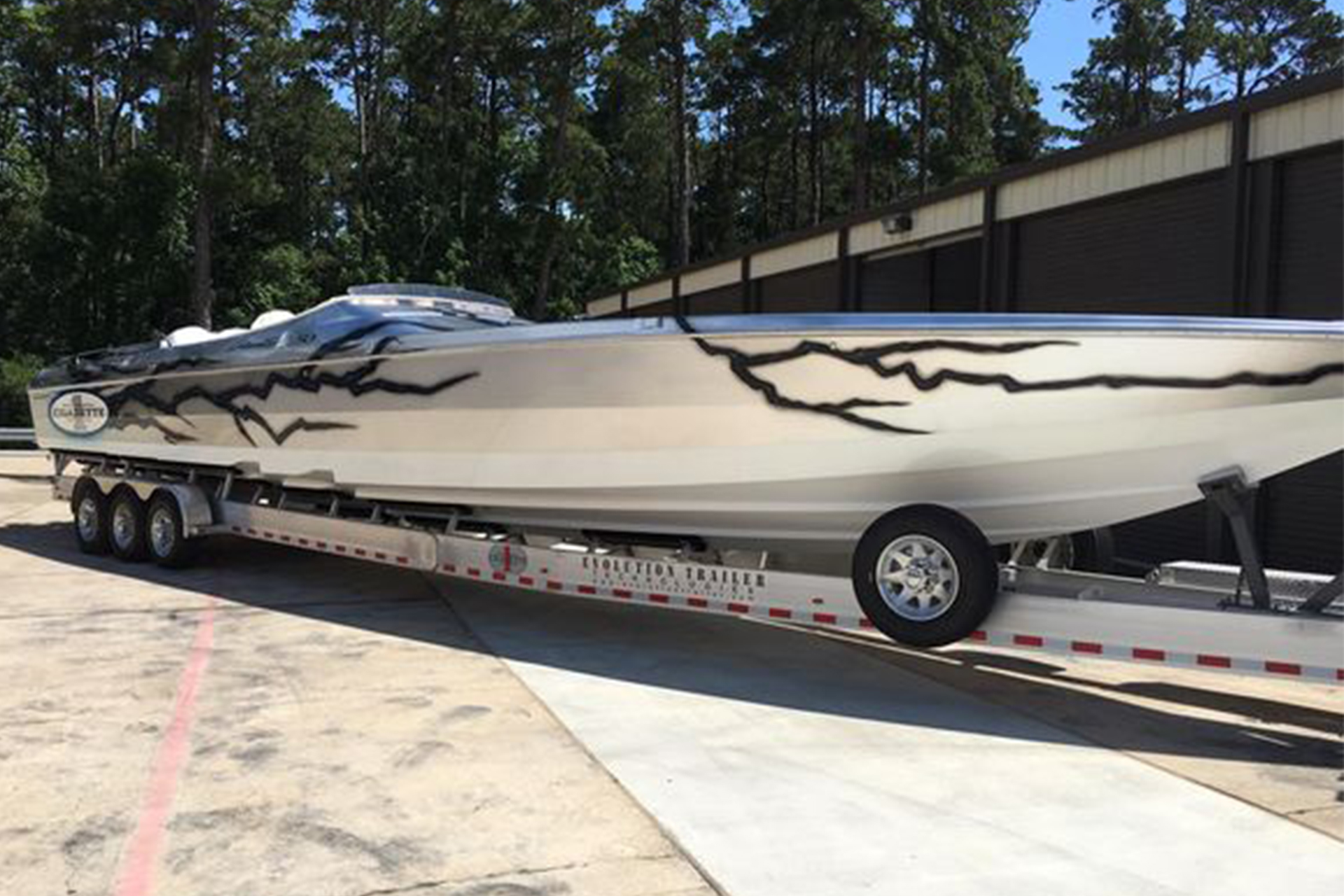 Custom cigarette boat with black lightning decal on trailer.